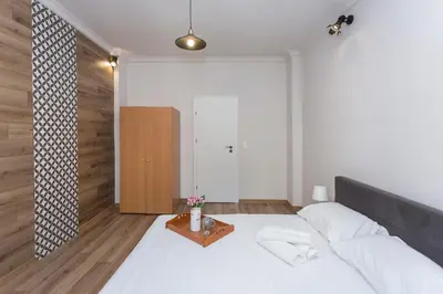 a bedroom with a white bed and a wooden wall at Sunny and Modern 1BDR Apartment in the Center in Sofia
