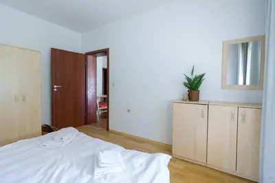 a bedroom with a white bed and wooden cabinets at Todorka Apartments in Bansko in Bansko