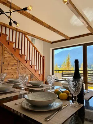 a wooden table with plates and wine glasses on it at Luxury Apartment Pirin Chalet in Terra Complex in Bansko