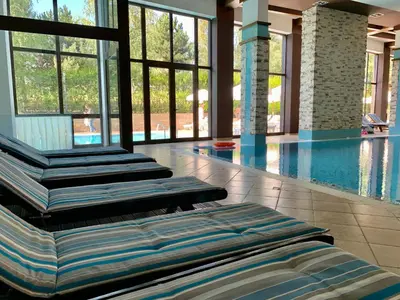 a swimming pool with several chaise lounges in a building at Luxury Apartment Pirin Chalet in Terra Complex in Bansko