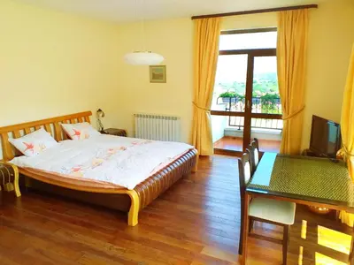 a bedroom with a bed and a table and a television at Стаи за Гости Lavender Lozen in Lozen