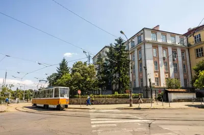 a yellow bus driving down a street next to a building at Exclusive Top Central Studio in Sofia