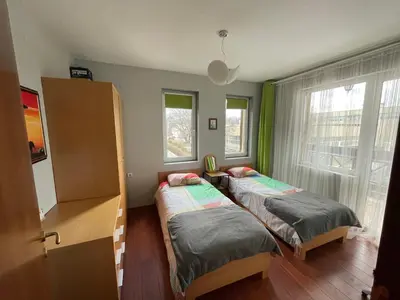 two beds in a room with two windows at Lovely 2-bedroom serviced apartment with SPA in Bansko
