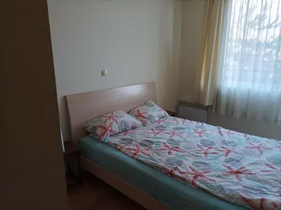 a bedroom with a bed with a blue comforter and a window at Apartment Detelina Residence in Bansko