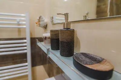 a bathroom shelf with a bottle of soap and a mirror at New & Comfortable home in Blagoevgrad center in Blagoevgrad