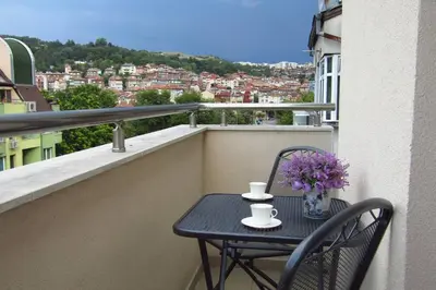 a black table and chair on a balcony with flowers at New & Comfortable home in Blagoevgrad center in Blagoevgrad