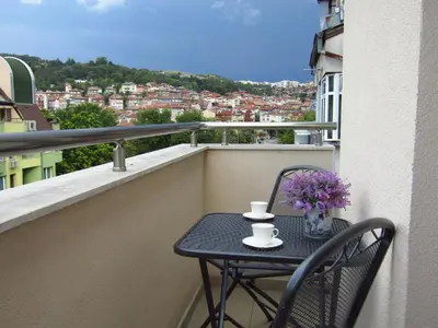 a table with two cups and flowers on a balcony at New & Comfortable home in Blagoevgrad center in Blagoevgrad