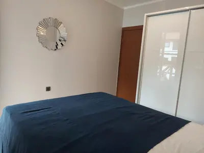 a bedroom with a blue bed and a clock on the wall at Monteverde Ski Lift Apartment Bansko in Bansko