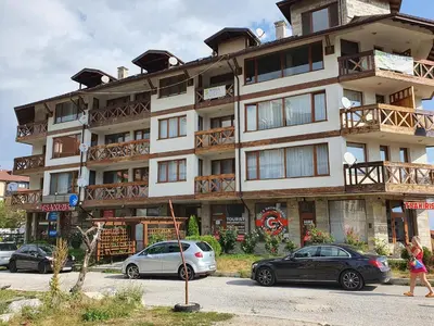 a large building with cars parked in front of it at Monteverde Ski Lift Apartment Bansko in Bansko