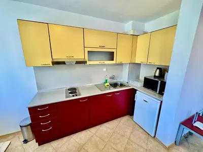 a kitchen with red cabinets and a white refrigerator at Todorini Kuli Apartments in Bansko