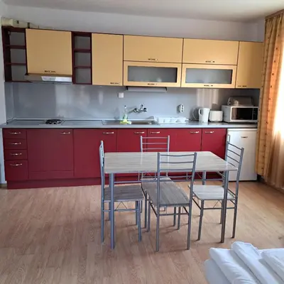 a kitchen with red cabinets and a table and chairs at Todorini Kuli Apartments in Bansko