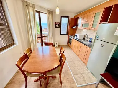 a kitchen with a wooden table and a refrigerator at Todorini Kuli Apartments in Bansko