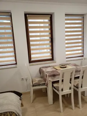 a dining room with a table and chairs and two windows at Ski-in ski-out Studio 2A7 Grand Monastery in Pamporovo