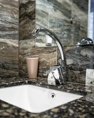 a white sink in a bathroom with a faucet at Sunny Apartment in Studentski grad, behind UNSS in Sofia