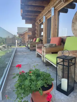a patio with couches and flowers on a house at ECO HOUSES ART OF LIVING - Еко къщи изкуството да живееш in Pamporovo