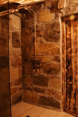 a shower in a room with a stone wall at ECO HOUSES ART OF LIVING - Еко къщи изкуството да живееш in Pamporovo