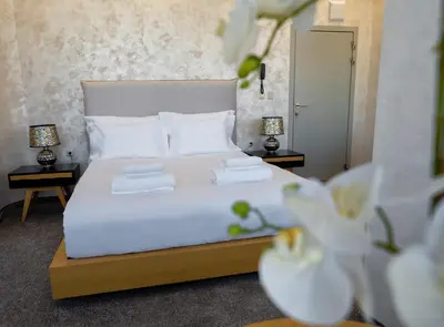 a bedroom with a white bed with two night stands at Hotel CITY Petrich in Petrich