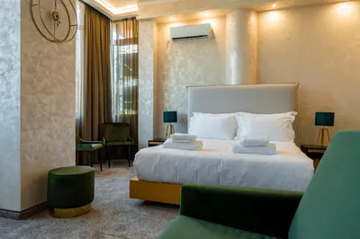 a bedroom with a large white bed and a green chair at Hotel CITY Petrich in Petrich