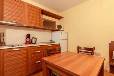 a kitchen with wooden cabinets and a table and a refrigerator at Studio by Mountain Lakes in Ezerovo