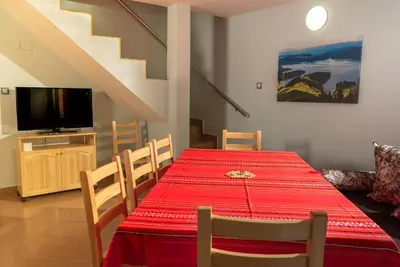 a dining room with a red table and a television at Почивна станция Сомат in Dospat