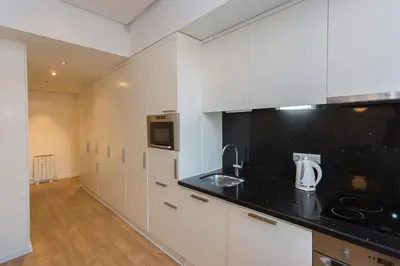 a kitchen with white cabinets and a black counter top at Modern Apartment in the City Center in Sofia