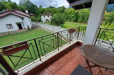 a balcony with a chair and a view of a yard at Двете къщи в планината in Beli Osŭm
