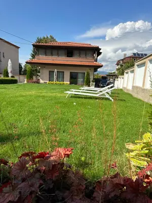 a house with a yard with a green lawn at Stella Guesthouse in Sapareva Banya