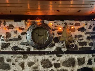 a clock on the side of a stone wall with lights at Музикалната къща in Breze