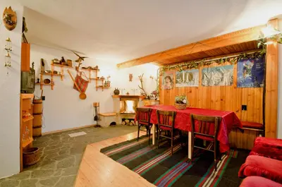 a dining room with a red table and chairs at Palyongov Guest House in Chepelare