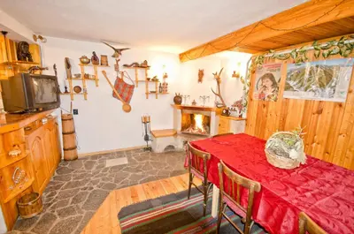 a dining room with a red table and a fireplace at Palyongov Guest House in Chepelare