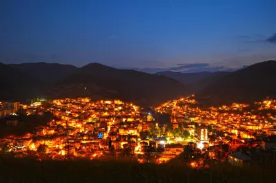 a city lit up at night with mountains at Palyongov Guest House in Chepelare
