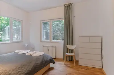 a bedroom with a bed and a chair and windows at Bright Apartment in the Heart of the City by Flat Mаnager in Sofia