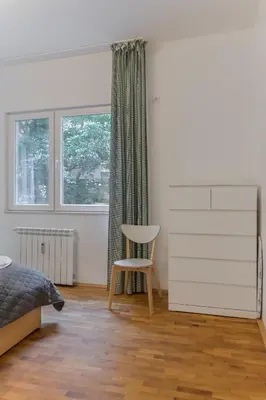 a bedroom with a bed and a chair and a window at Bright Apartment in the Heart of the City by Flat Mаnager in Sofia