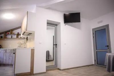 a kitchen with a white wall with a sliding door at Апартаменти ЗДРАВЕ in Sapareva Banya