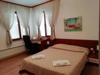 a bedroom with two beds and a desk and windows at Къща в центъра на Стрелча, джакузи с минерална вода in Strelcha