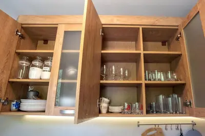 a kitchen cabinet with glasses and dishes in it at ТАНГЕНТА стаи за гости in Oreshak