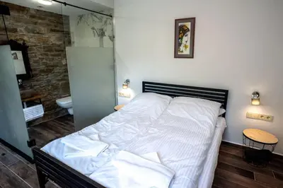 a bedroom with a white bed and a bathroom at ТАНГЕНТА стаи за гости in Oreshak