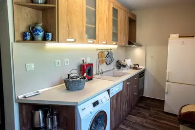 a kitchen with a washing machine and a refrigerator at ТАНГЕНТА стаи за гости in Oreshak