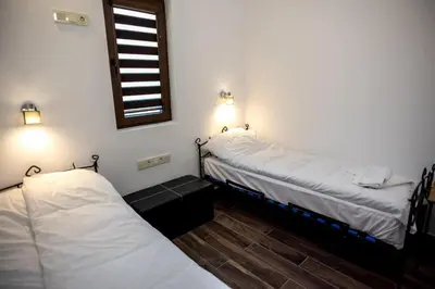 two beds in a room with white sheets and a window at ТАНГЕНТА стаи за гости in Oreshak