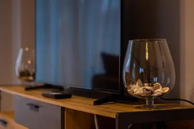 a wine glass sitting on a table in front of a tv at Apartment City Home in Sofia