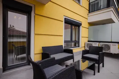 two chairs sitting on a patio next to a yellow building at Apartment City Home in Sofia