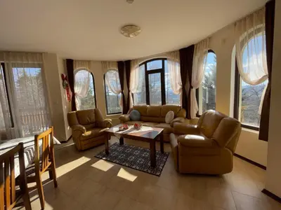 a living room with couches and a table and windows at Cassiopea Villas in Pamporovo