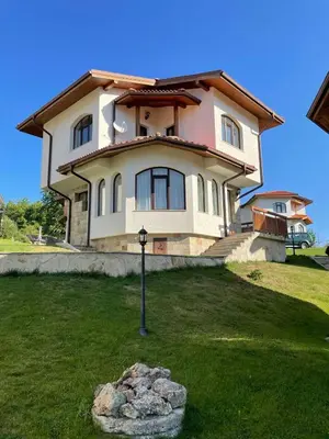 a large house on top of a green lawn at Cassiopea Villas in Pamporovo