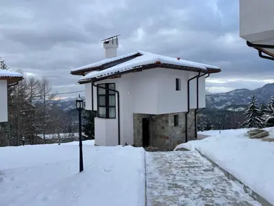 a small white building with snow on top of it at Cassiopea Villas in Pamporovo