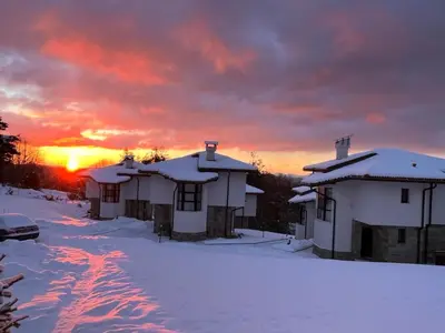a group of houses in the snow at sunset at Cassiopea Villas in Pamporovo