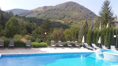 a pool with chairs and a mountain in the background at Hotel Perfect in Yamna