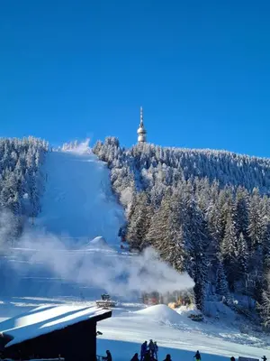 a snow covered hill with a lighthouse in the distance at Студиа Студенец in Smolyan
