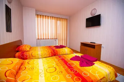 a bedroom with two beds and a flat screen tv at Семеен Хотел Надежда in Razlog