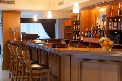 a bar with a bunch of bottles and chairs at Hotel Astrea in Hisarya