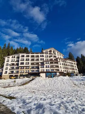 a large white apartment building in the snow at Родопски Рай in Pamporovo